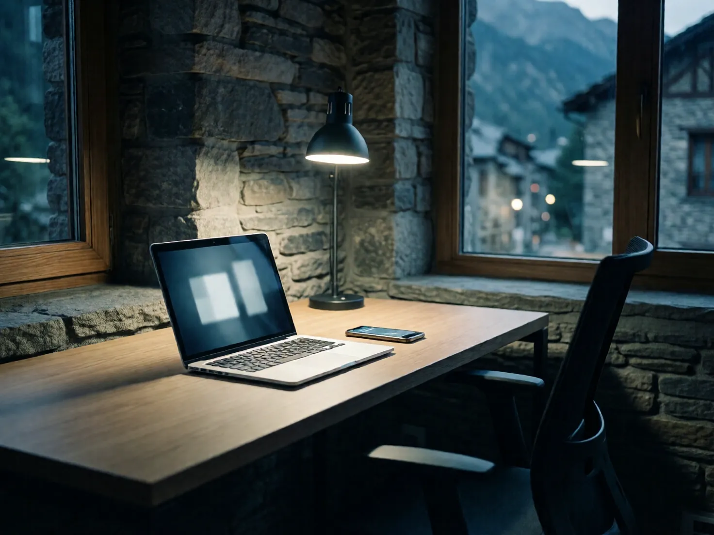 Estudio vacío de noche: el portátil y el móvil siguen trabajando solos